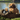 A light brown long-haired Dachshund dog standing on a log with an Ancol plush sloth dog toy with a dark grey body, next to the dog. With a lake pictured in the background. 