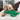 Poodle-cross type dog laying is head on a green Ancol Made From Turtle dog toy, pictured on a cream sofa, with brown cushions.