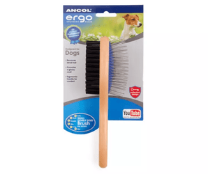White background with a side on view of a small wooden handled Ergo Double-sided Brush for dogs, showing both a metal bristle side and a soft bristle side attached to cardboard packaging.