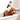 Brown poodle type dog in a bath tub,  with a hand holding a bottle of Animology Curly Coat Shampoo above the dog's back. 