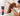 Brown poodle type dog in a bath tub, with a woman holding a shower head over the back of the dog. In the foreground is a black and red bottle of Animology Dogs Body Shampoo.