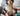 Blue Marl collie dog sat on a grey sofa, with a someone brushing them, sat next to a black and aqua blue spray bottle of Animology Knot Sure detangle spray. 