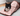An adult black and white cat sat inside a  Battersea Peek-A-Boo Sack in a living room with a grey sofa. 