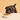 A small black dog with curly fur leans over a white bowl of Calibra Premium dry kibble against a warm beige background.