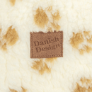 Close up of a cream cat bed with brown pawprints with a central brown tag which says 'Danish Design'. 