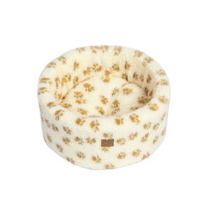 White background with a round cream cat bed with brown pawprints. 
