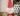 Christmas presents with a Gonk plush dog toy with red and white stripy hat and red rope legs, with a white beard and white bobble on the hat , sat in the foreground.