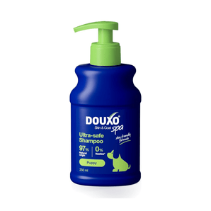 White background with a blue bottle of Douxo Ultra-safe Puppy Shampoo with a green pump. 