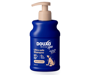 White background with a blue bottle of Douxo Ultra-safe Shed Control Shampoo with a beige pump. 