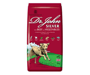 White background with a red bag of Dr.John Silver Beef and Vegetables dry food. Pictured on the bag is an illustrated Labrador dog in a farm field. 