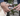 Picture of a person's hands cleaning their Golden Retriever dog's teeth using a white dual ended toothbrush for cats and dogs. 