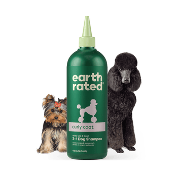 White background with a green bottle of Earth Rated Curly Coat Dog Shampoo, additionally on the bottle is text 'White tea & basil, 3 in 1 Dog Shampoo'. A Yorkshire terrier is pictured on the left and a black standard poodle is on the right of the bottle. 