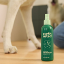 A green spray bottle of Earth Rated Deodorising Dog Refesh Mist in the foreground, with two white dogs pictured in the background.