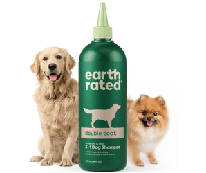 White background with a green bottle of Earth Rated Double Coat Dog Shampoo, additionally on the bottle is text 'White tea & basil, 3 in 1 Dog Shampoo'. A Golden Retriever dog is pictured on the left and a Pomeranian dog is on the right of the bottle. 