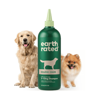 White background with a green bottle of Earth Rated Double Coat Dog Shampoo, additionally on the bottle is text 'White tea & basil, 3 in 1 Dog Shampoo'. A Golden Retriever dog is pictured on the left and a Pomeranian dog is on the right of the bottle. 