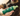 Hand holding a green pump bottle of Earth Rated No-Rinse Dog Shampoo in the foreground, with a black, tan and white dog pictured in the background.