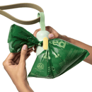 White background with hands holding a dog lead with a light green Earth Rated poop bag dispenser attached. Attached to the dispenser is a poop bag.  