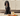 A black spaniel sits on a cream rug in a kitchen setting, with a bowl of food, a carrot, and a Forthglade chicken dog food box placed in front of it.
