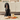 A black spaniel sits on a cream rug in a kitchen setting, with a bowl of food, a carrot, and a Forthglade chicken dog food box placed in front of it.