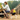 Lady sat at a picnic table with a Jack Russell terrier on a red Halti Active lead in the foreground. 
