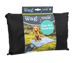 Henry Wag Easy-roll travel bed packed up in black bag in a cardboard sleeve with text 'Henry Wag, Active Paws Outdoors, Easy-roll Travel Bed' with a picture of a red Labrador dog lying on the mat. Pictured on a white background. 