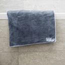 Bath tub with a Henry Wag Pet Cleaning Towel hanging over the tiled edge. 