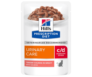Hills Prescription cat food pouch with a bowl full of food pictured on the packet, text reads 'Urinary Care, C/D Multicare Stress' and 'Tender chunks in Gravy with Salmon' on a white background. 