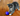 Grey tabby and white kitten playing a purple KONG Active Cat treat toy, on a wooden floor. 