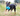 Black and tan young adult dog playing with a blue KONG Jumbler Football, in a grass area.