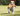 Jack Russell terrier carrying plush orange fox with white underside rope dog toy outside on grass. 