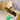 Golden retriever playing with a KONG Shakers Bobz Duck dog toy, with a long green neck and brown body, yellow beak and legs with stitched features on a grey sofa.