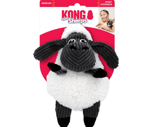 White background with a KONG Floofs Sherps Sheep dog toy, the main body is made from white sherpa with black legs and head with stitched features attached to a cardboard backing.