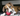 Brown and white boxer puppy playing with a red KONG Stuff-A-Ball in a living room environment. 