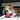 Brown and white boxer puppy playing with a red KONG Stuff-A-Ball in a living room environment. 