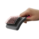 White background with a hand holding a medium black plastic brush with pink grip handle and plastic bristles with red tips pictured. 