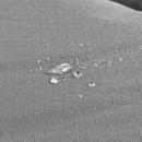 Close up of a Bolster-type grey dog bed with water droplets pictured on the waterproof surface. 