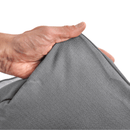 White background with a hand lifting the corner of a bolster-type grey dog bed to show the underside. 
