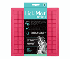 White background with a pink LickiMat Playdate slow feeder mat with a square grid surface. The Playdate mat is in black and blue packaging cardboard packaging. 