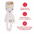 White bear shaped dog toy with long arms and legs, stitched detail eyes, brown nose with tags attached to top and mid-section. Red text along side picture of bear says 'Crinkle body to engage your pup!', 'Hidden squeaker for extra engagement', 'Not-stuffed - fill the tummy with an object that holds a comforting scent!' Pictured on a white background. 
