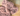 Close up of dusky pink elephant shaped dog toy with long arms and legs, stitched detail eyes on a wooden floor. 