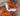 Close up of orange fox shaped dog toy with white chin and stitched detail eyes, brown nose, tags removed, pictured on a wooden floor. 