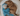 Brown spaniel type puppy cuddling with blue monkey shaped dog toy with long arms and legs, pale brown face and ears and stitched detail eyes. Pictured in a round cream fleecy dog bed. 