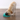A yellow Labrador retriever is eating from a Nina Ottosson teal pet slow feeder bowl with a clear plastic rolling tube, set on a brown wood-look floor against a white wall.
