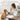 Woman and dog sitting on the floor with a tablet and framed picture, surrounded by home decor elements.