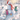A whimsical winter illustration showing a snowman in a red Santa hat and red scarf, surrounded by three sheep wearing colorful scarves in a snowy outdoor scene with trees, birds, and a small house in the background.