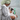 Black and white dog being held by a woman wearing a dressing grown, holding a green bottle of Pet Head Furtastic shampoo in a tiled bathroom. 