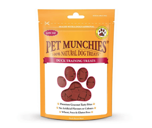 A stand-up pouch of Pet Munchies Duck training dog treats on a plain white background. The packaging is bright orange with a large paw-shaped window showing the duck training treats inside.