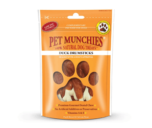 A packet of Pet Munchies Duck Drumsticks complementary dental chews for dogs, in an orange stand-up pouch with a paw print graphic and visible drumstick-shaped treats through a window.