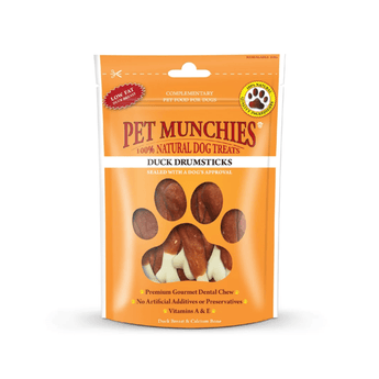 A packet of Pet Munchies Duck Drumsticks complementary dental chews for dogs, in an orange stand-up pouch with a paw print graphic and visible drumstick-shaped treats through a window.