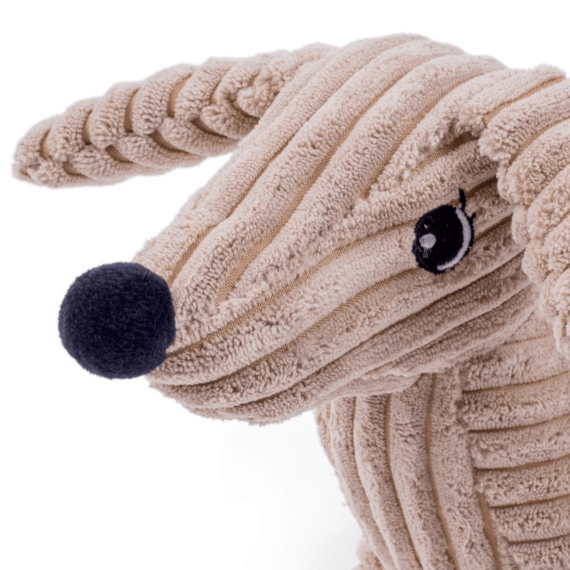 Close up of sausage dog style dog toy made from cord effect fabric with floppy ears and a round black fleece nose, stitch detailed eyes on a white background. 